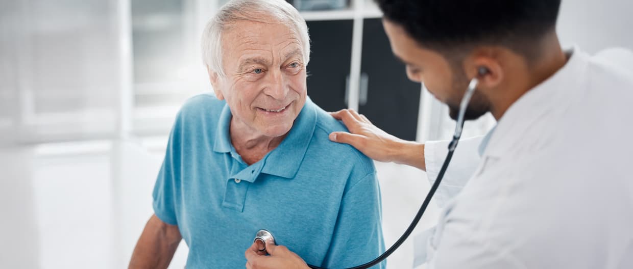 Doctor using stethoscope on older man